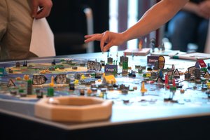 Am Spieletisch mit einer Hand, die eine Figur setzt.