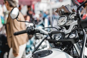 Ein Motorradcockpit. Dahinter unscharf mehrere Menschen.