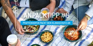 Gefäße gefüllt mit Speisen auf einer Picknickdecke. Personen sitzen drumherum.